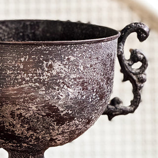 Decorative black urn with dried flowers on a wooden surface