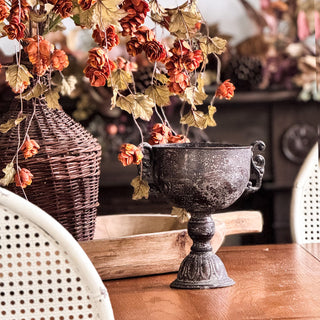 Decorative black urn with dried flowers on a wooden surface