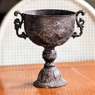 Decorative black urn with dried flowers on a wooden surface