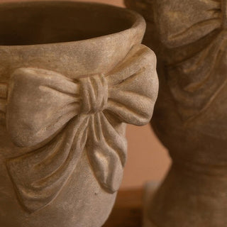 Close-up of decorative concrete urn with bow detail, vintage-inspired planter for farmhouse home styling