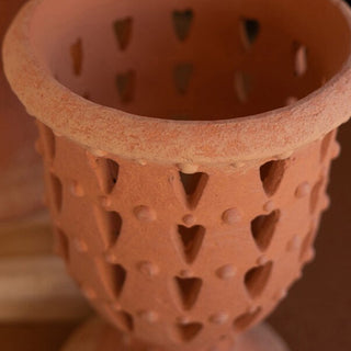 Close-up of terracotta perforated urn with heart-shaped cutouts, rustic farmhouse planter detail