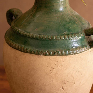 Close-up of terracotta and green clay urn with two handles, handcrafted rustic farmhouse vase texture