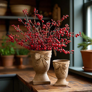 Set of two concrete urns with bow detail, styled with red berry branches for farmhouse holiday table decor