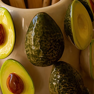 Detail of ceramic avocado vase featuring half and whole avocado designs with realistic texture and color