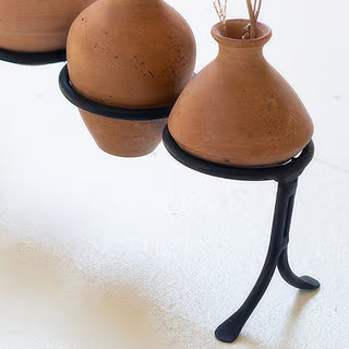 Side detail of clay vessels resting in curved iron stand holders