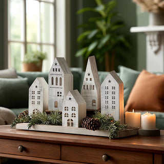  Distressed white wooden village houses set of 5 displayed on wood tray with pine branches, pinecones and candles for Christmas farmhouse mantel decor