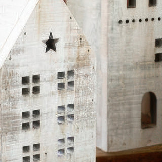 Detail view of distressed white wooden Christmas houses showing weathered finish texture and star cutout accents for rustic holiday decor