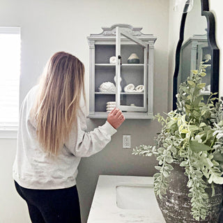Woman opening vintage gray wall cabinet
