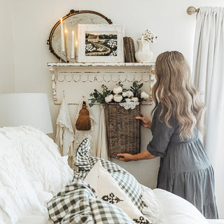 Woman styling distressed white wall shelf with hooks
