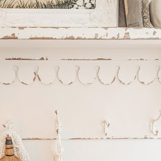 Distressed white wall shelf with metal hooks
